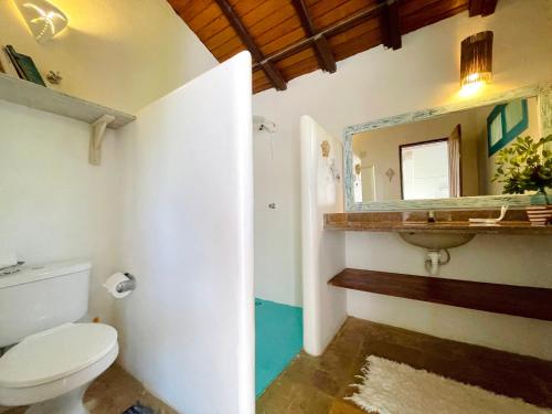 a bathroom with a toilet and a mirror at Espelho Bahia Blue House in Praia do Espelho