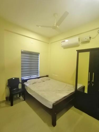 a bedroom with a bed and a chair and a window at Queens Residency in Trichūr
