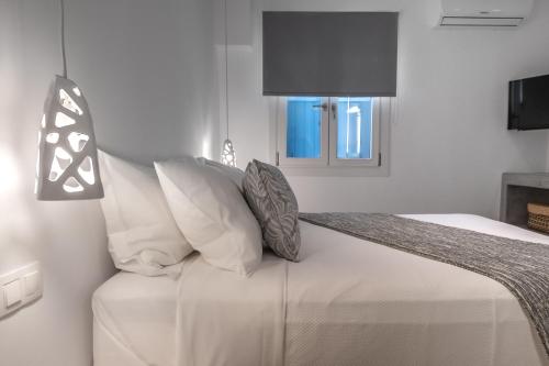 a bedroom with a bed with white pillows and a television at Manesis Suites in Pollonia