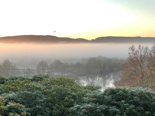 a misty morning with a view of a river and trees at The Observatory Annexe in Dorking