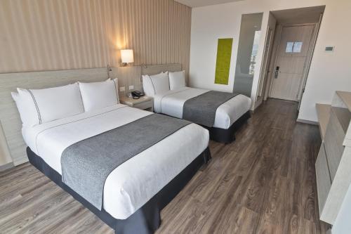 duas camas num quarto de hotel com pisos de madeira em Sonesta Hotel Ibagué em Ibagué