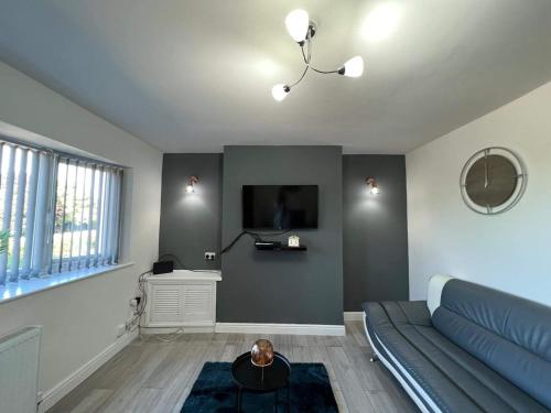 a living room with a blue couch and a tv at Cosy, Modern Home Near BHX, NEC and City Centre in Birmingham