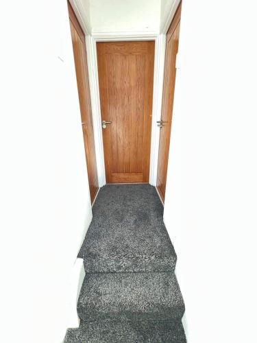 a hallway with a wooden door and a carpet at Cosy, Modern Home Near BHX, NEC and City Centre in Birmingham