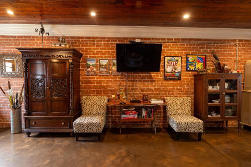 a living room with two chairs and a tv on a brick wall at Bayou Chateau in New Iberia