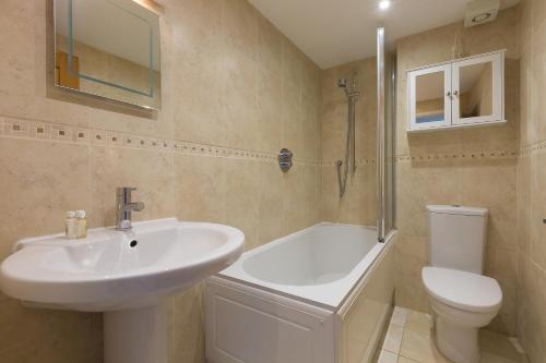 a bathroom with a sink and a tub and a toilet at Ocean Gate in Carbis Bay