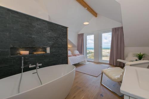a bathroom with a white tub and a black wall at Beach View in St Ives