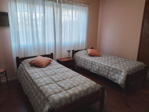 twee bedden in een kleine kamer met een raam bij Feliz Estadia in Mendoza