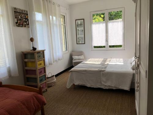 une chambre avec un lit et deux fenêtres dans l'établissement Maison familiale- jardin & piscine-600m plage, à Saint-Palais-sur-Mer