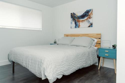 a white bedroom with a bed and a blue nightstand at Cheerful 3 Bedroom near USU - Inspiring Memories in Logan