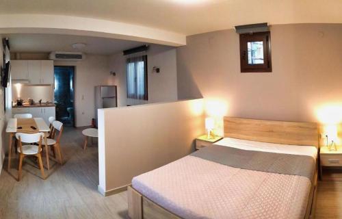 a bedroom with a bed and a table and a kitchen at Guesthouse Kastelia in Kalabaka