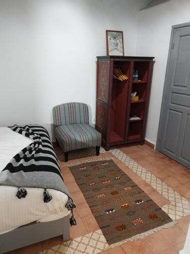 a bedroom with a bed and a chair and a rug at RIAD MAROSKO in Essaouira