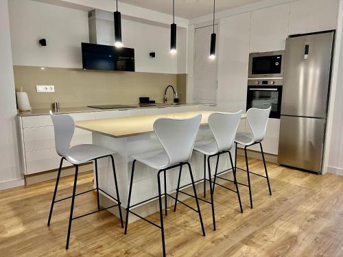 eine Küche mit einem Tisch mit weißen Stühlen und einem Kühlschrank in der Unterkunft Piso Exclusivo en Vigo céntrico, negocios, confort in Vigo