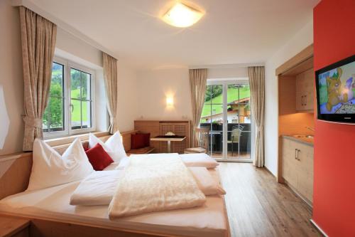 a bedroom with a bed with white sheets and a tv at Hotel Garni Ingeborg in Westendorf