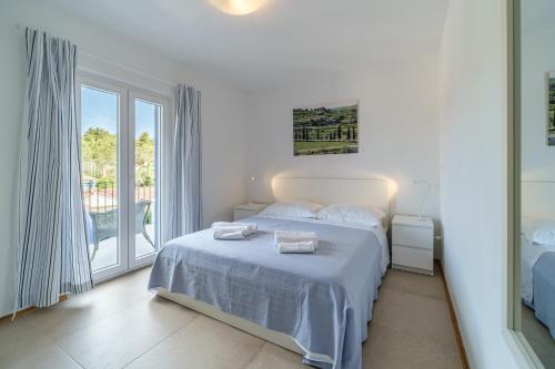 a white bedroom with a bed and a large window at ameli in Milna