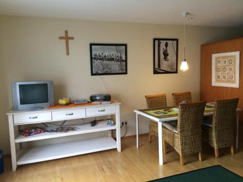 a living room with a table with a television and a cross on the wall at Ferienresidenz Am weißen Regen in Bad Koetzting