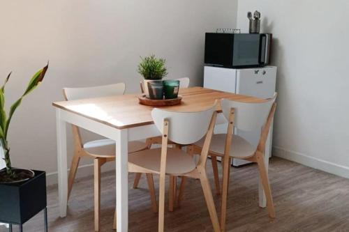 a dining room table with four chairs and a microwave at Agréable duplex Gare in Le Mans