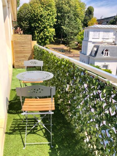 une table et des chaises sur un balcon avec une haie dans l'établissement Luxueux Appartement Trouville/Deauville avec balcon, à Trouville-sur-Mer