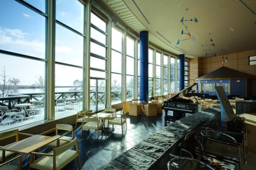 a restaurant with tables and chairs and large windows at Biwako Ryokusuitei in Otsu