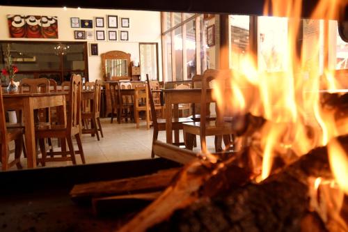 a fire burns in a restaurant with tables and chairs at Lizzy Wasi Urubamba in Urubamba