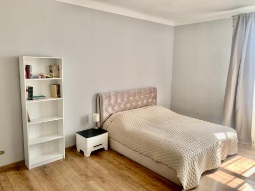 biała sypialnia z łóżkiem i półką na książki w obiekcie Two bedroom apartment Barinu street w mieście Lipawa