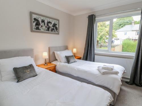 two beds in a room with a window at Rose Cottage in Barnard Castle