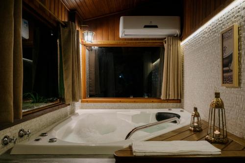 a bath tub in a bathroom with a window at Chalés Requinte da Mantiqueira in Monte Verde