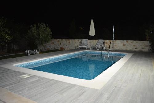 a swimming pool at night with two chairs and an umbrella at Casa da Pedra in Ansião