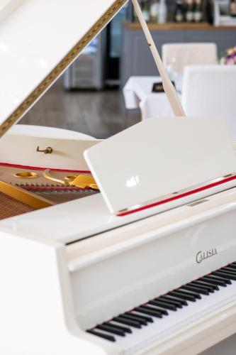 a white piano with a laptop on top of it at Hotel Europejski in Nysa