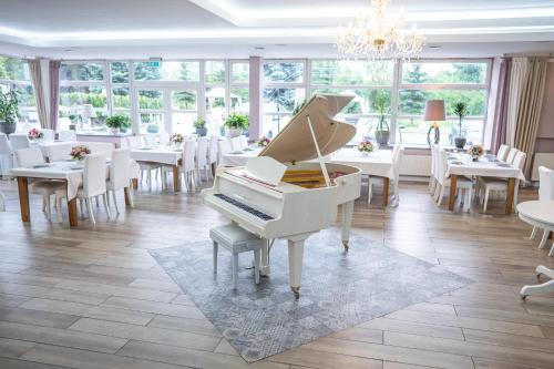 a white piano in a dining room with tables and chairs at Hotel Europejski in Nysa
