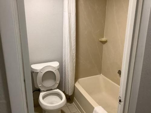 La petite salle de bains est pourvue de toilettes et d'une baignoire. dans l'établissement Heritage Park Inn, à Kissimmee