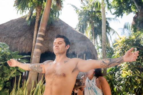 a man with a tattoo on his arm in front of a house at The Reef Playacar Beach Resort & Spa-Optional All Inclusive in Playa del Carmen