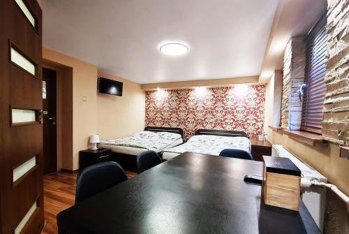 um quarto com duas camas e uma mesa e cadeiras em Najlepsze Miejsce - pokoje i apartamenty w Krakowie em Cracóvia