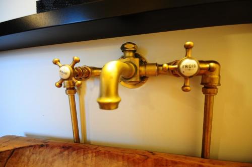 a gold faucet on a wall next to a sink at Maison d'Hôtes Cerf'titude in Érezée