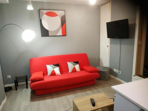 czerwona kanapa w salonie z telewizorem w obiekcie Plénitude terrasse w mieście Le Mans