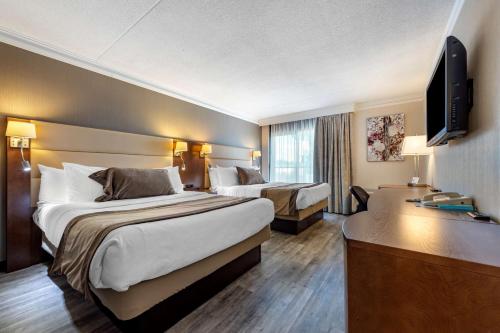 a hotel room with two beds and a television at Best Western Hotel Universel Drummondville in Drummondville