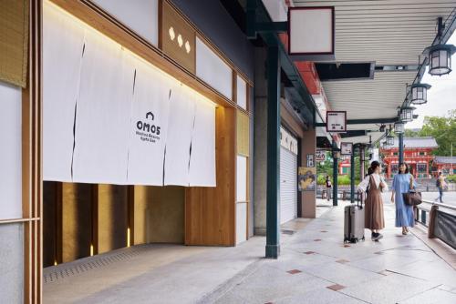 Due persone che camminano lungo un marciapiede davanti a un negozio di OMO5 Kyoto Gion by Hoshino Resorts a Kyoto