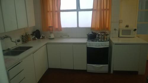 a small kitchen with a stove and a microwave at Habitación con baño privado Un piso por escalera in Buenos Aires