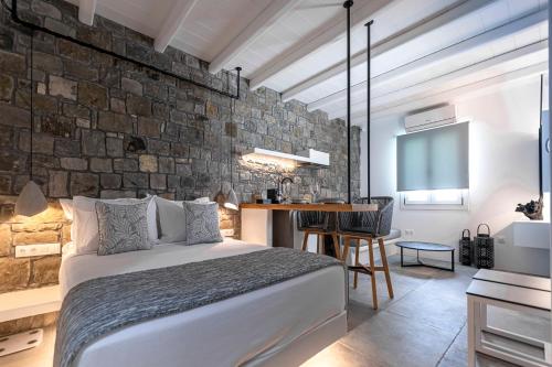 1 dormitorio con cama y pared de piedra en Manesis Suites en Pollonia