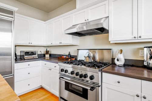 a kitchen with white cabinets and a stove top oven at Golden Getaway in Summerland