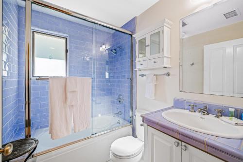 een blauwe betegelde badkamer met een wastafel en een douche bij Golden Getaway in Summerland