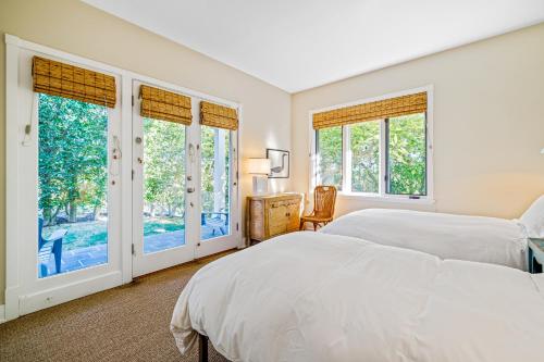 a white bedroom with a bed and windows at Golden Getaway in Summerland