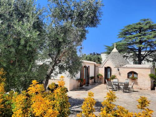 an exterior view of a house with a patio and trees at Trullo Leone in Martina Franca