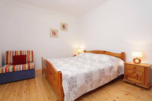 a bedroom with a large bed and a chair at Apartments by the sea Korcula - 6016 in Korčula