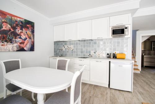 a kitchen with white cabinets and a white table and a table at Mar Apartments Alicante, Playa de San Juan in Alicante