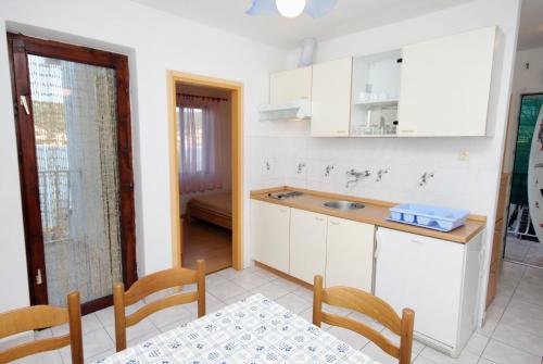 a kitchen with white cabinets and a table and chairs at Apartments by the sea Vinisce, Trogir - 5982 in Vinišće