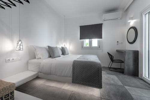 a white bedroom with a bed and a desk at Manesis Suites in Pollonia