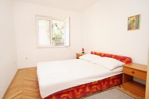 a white bed in a room with a window at Apartment Baska Voda 6057c in Baška Voda