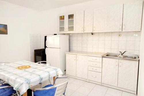 a kitchen with a sink and a white refrigerator at Apartment Baska Voda 6057c in Baška Voda