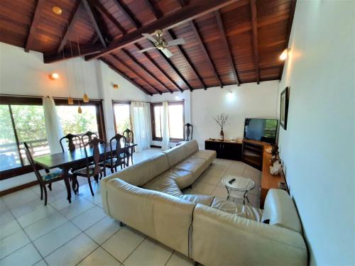 a living room with a couch and a dining room at 3Suítes, piscina e vista do mar em condomínio pé na areia - pátio compartilhado in Búzios