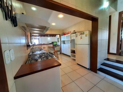 a kitchen with a stove and a refrigerator at 3Suítes, piscina e vista do mar em condomínio pé na areia - pátio compartilhado in Búzios